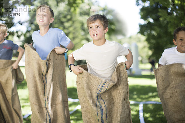 Jungen  die an einem Sackhüpfen teilnehmen.