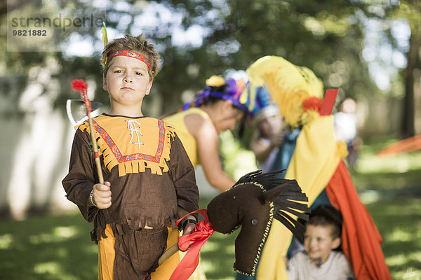 Porträt eines Jungen im Garten  der Cowboys und Indianer spielt.