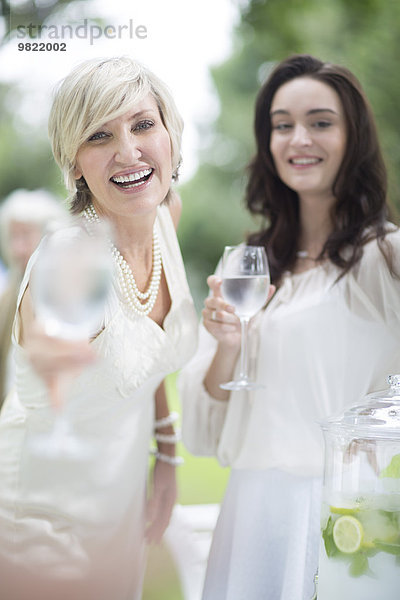 Zwei lächelnde Frauen mit Weingläsern im Freien
