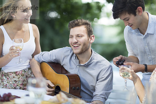 Glückliche Freunde mit Wein und Gitarre im Freien