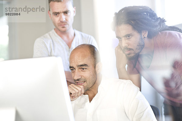 Drei Kollegen beim Blick auf den Bildschirm im Büro