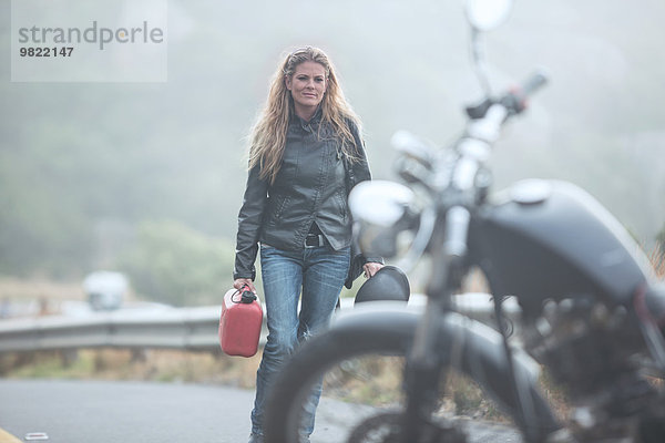 Frau mit Benzinkanister auf dem Motorrad unterwegs