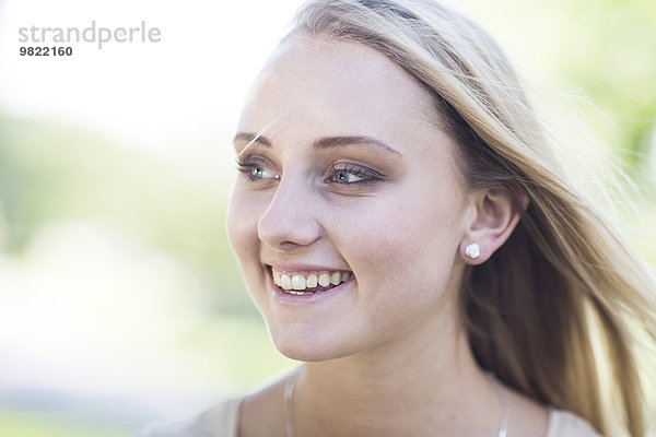 Porträt einer lächelnden blonden jungen Frau im Freien