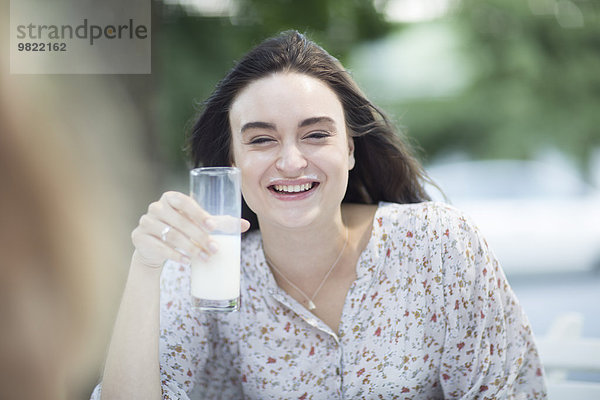 Glückliche junge Frau mit Milchschnurrbart im Freien