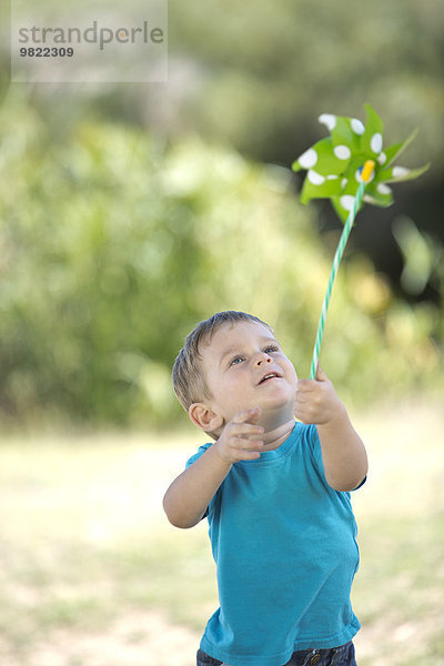 Kleiner Junge im Freien spielt mit Papierwindmühle