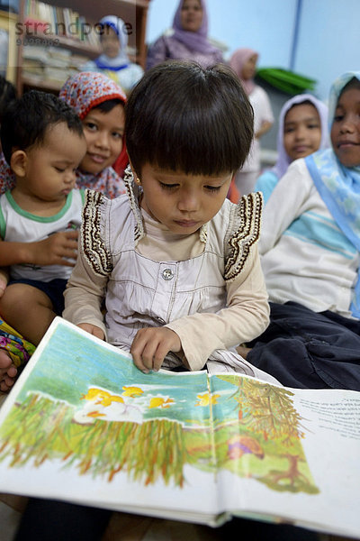 Mädchen schaut ein Bilderbuch an  Dorf Gampong Nusa  Aceh  Indonesien  Asien