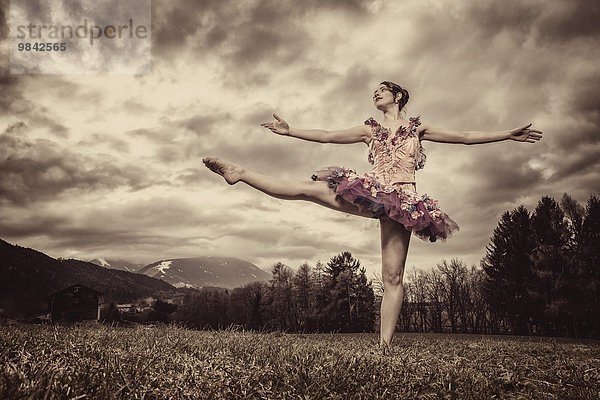 Ballerina mit Tutu tanzt vor wolkigem Himmel