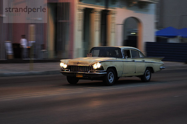 Taxi  fahrender amerikanischer Oldtimer auf dem Malecón  Dämmerung  Centro Habana  Havanna  Ciudad de La Habana  Kuba  Nordamerika