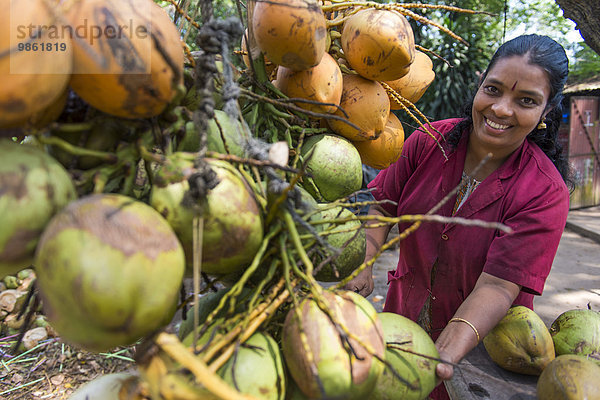 Junge Frau verkauft Kokosnüsse an der Straße  Kochi  Kerala  Indien  Asien