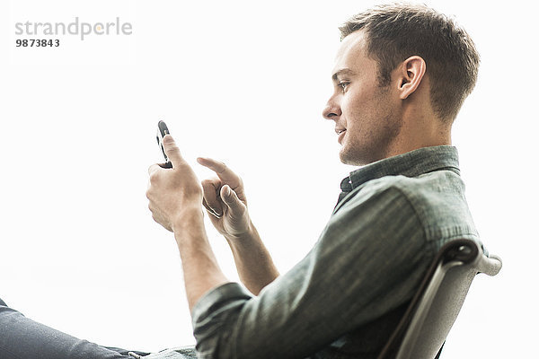 Ein Mann sitzt und überprüft sein Telefon.