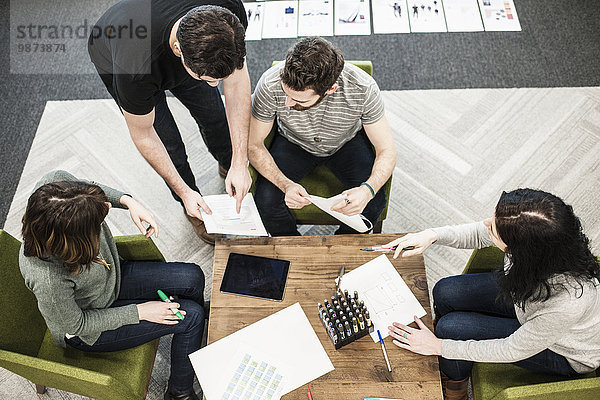 Vier Personen  die mit Farbstiften auf Papier an einem Tisch saßen  Kollegen bei einer Planungssitzung.
