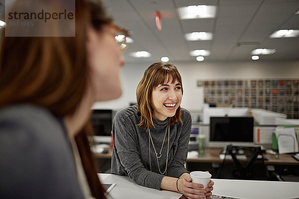 Zwei Frauen sitzen in einem Büro und unterhalten sich.