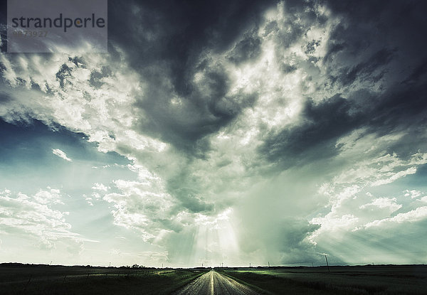 Eine Straße  die bis zum Horizont reicht  unter einem dramatischen Himmel.