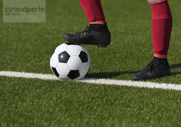 Fußballer hält Ball mit Fuß  Nahaufnahme