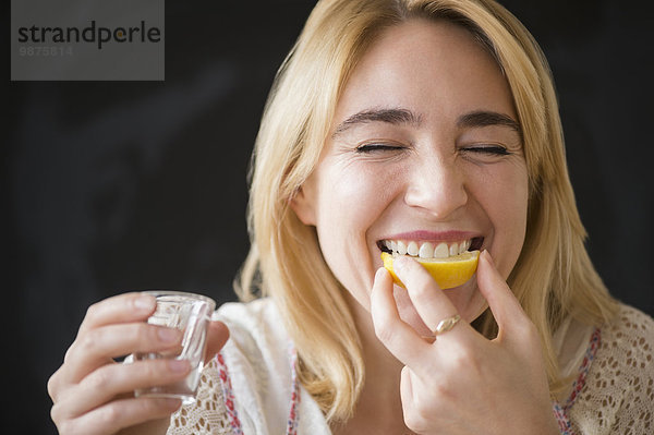 Europäer Frau Alkohol Scheibe Zitrusfrucht Zitrone schießen essen essend isst