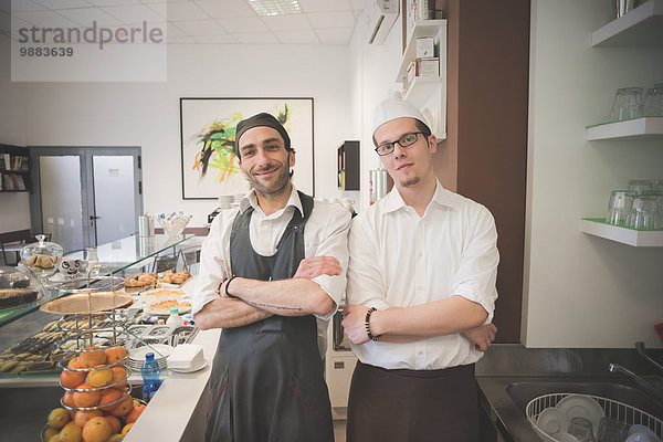 Kellner mit gekreuzten Armen im Café