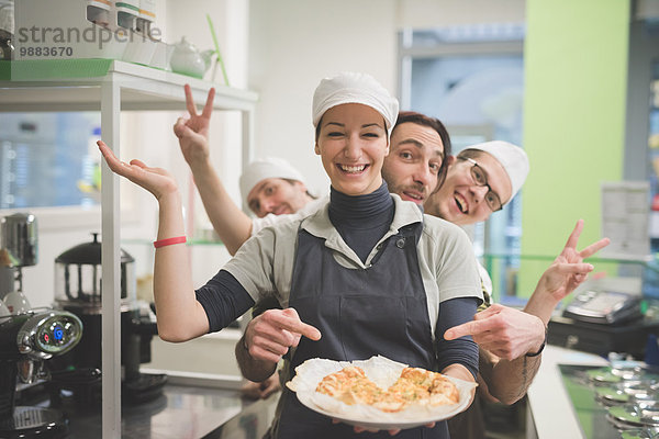 Kellnerin mit einem Teller mit Essen  Kollegen  die sich hinterher lustig machen.