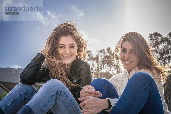Porträt zweier junger Freundinnen am luftigen Strand