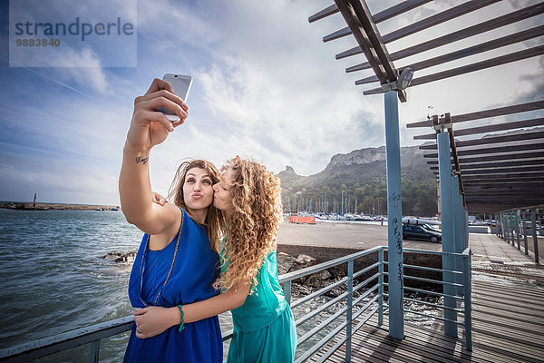 Zwei junge Freundinnen  die Smartphone Selfie am Pier nehmen
