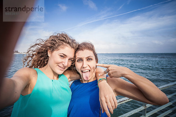 Zwei junge Freundinnen nehmen Selfie am Pier.