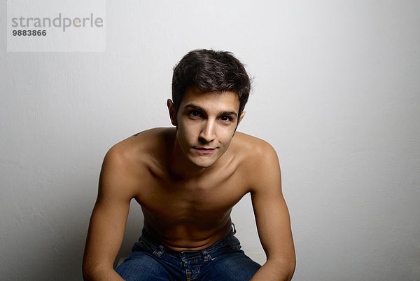 Studio-Porträt eines selbstbewussten jungen Mannes mit nackter Brust