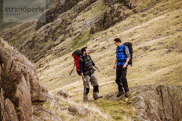 Zwei junge männliche Wanderfreunde beim Lachen und Plaudern  The Lake District  Cumbria  UK