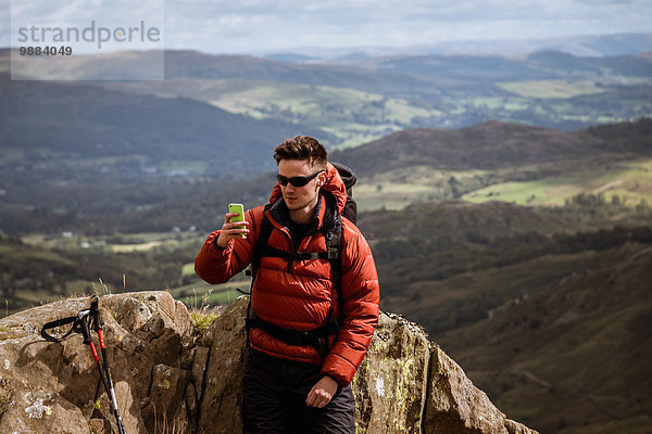 Junge männliche Wanderer nehmen Smartphone Selfie vom Berg  The Lake District  Cumbria  UK