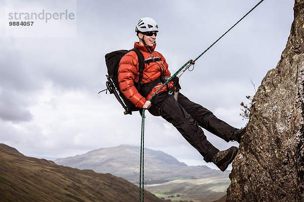 Junge männliche Kletterer beim Abseilen am Fels  The Lake District  Cumbria  UK