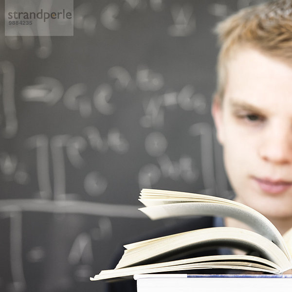 Junger Mann liest Mathebuch