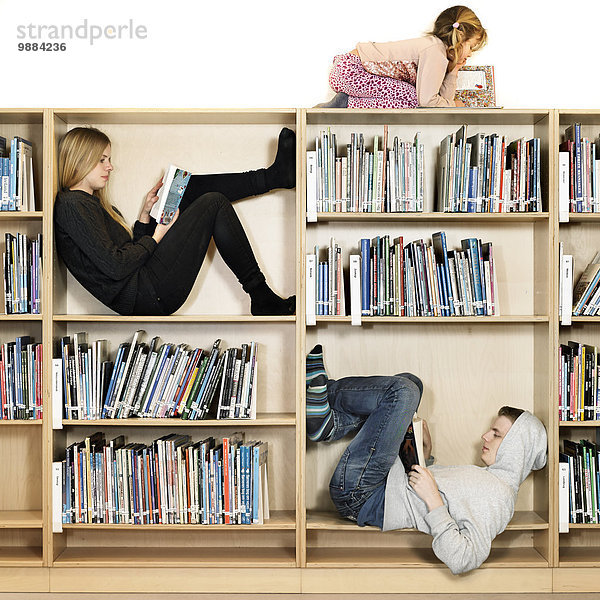 Geschwister lesen im Bücherregal