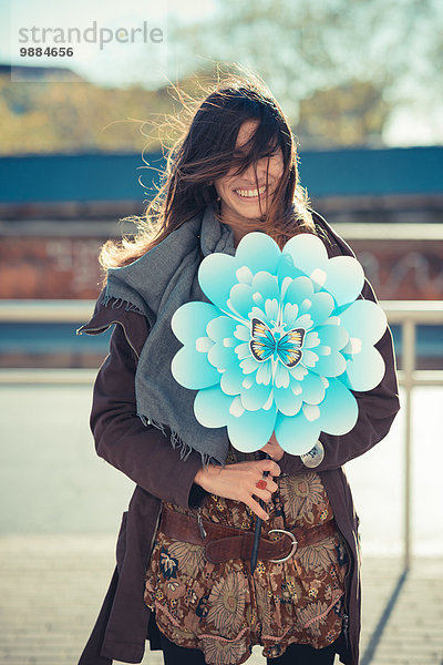Porträt einer mittleren erwachsenen Frau mit Blumenwindmühle