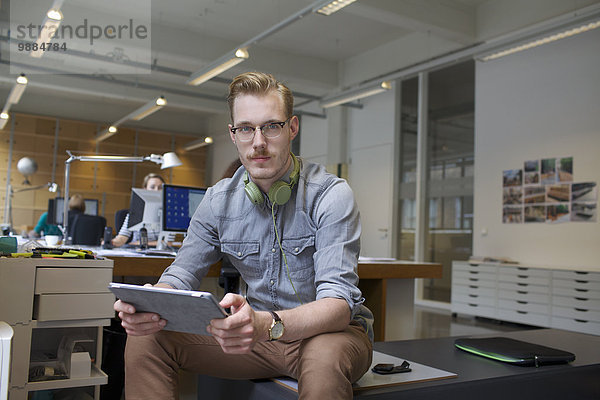 Porträt eines jungen Mannes mit digitalem Tablett im Büro