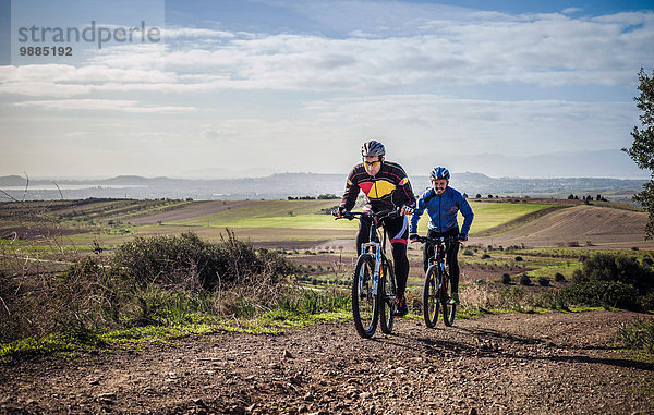 Zwei männliche Mountainbiker  die auf einem Feldweg fahren  Cagliari  Sardinien  Italien