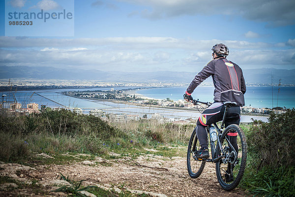 Rückansicht des männlichen Mountainbikers vom Küstenweg aus  Cagliari  Sardinien  Italien