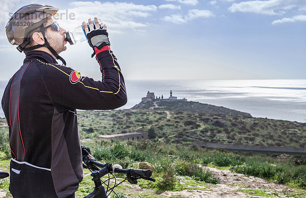 Mittlerer Erwachsener  männlicher Mountainbiker  Trinkwasser auf dem Küstenweg  Cagliari  Sardinien  Italien