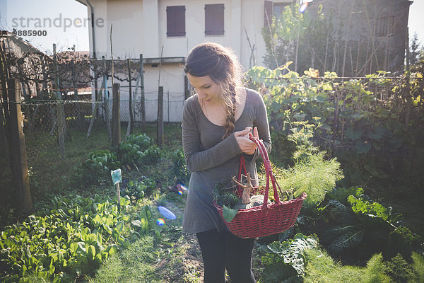 Junge Frau hält Korb im Garten