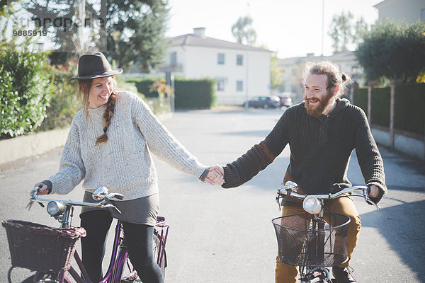 Junges Paar beim Radfahren  Händchen haltend