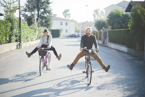 Junges Paar beim Radfahren mit ausgefahrenen Beinen