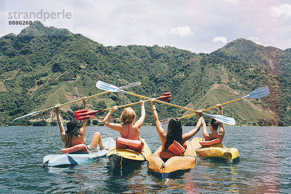 Rückansicht von vier Freundinnen  die im Kajak auf dem Lake Atitlan  Guatemala  feiern.