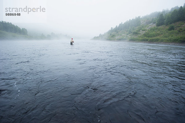 Mann Dunst Landschaftlich schön landschaftlich reizvoll Fluss Bach angeln Forelle breit