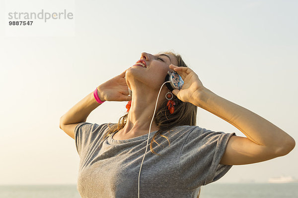 junge Frau junge Frauen zuhören Strand Kopfhörer Musik Klassisches Konzert Klassik