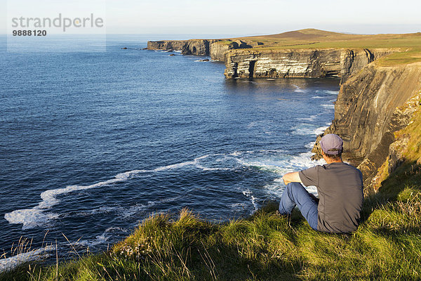 Felsbrocken sitzend Mann Ecke Ecken Sonnenuntergang Steilküste Küste dramatisch Ignoranz vorwärts Wiese Clare County Irland