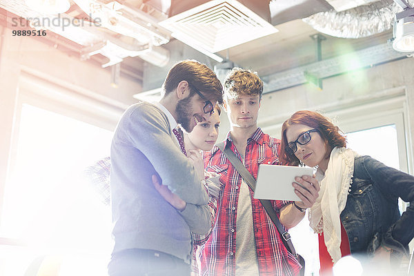 Kreative Geschäftsleute teilen sich ein digitales Tablett im sonnigen Büro