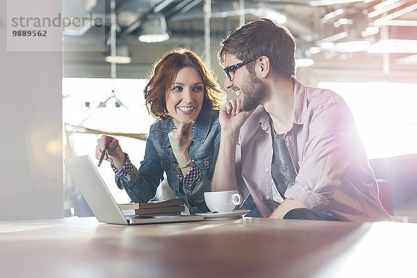 Lächelnde Geschäftsleute  die am Laptop arbeiten