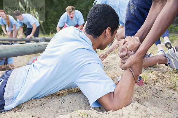 Teamkollege hilft Mann auf Boot Camp Kurs