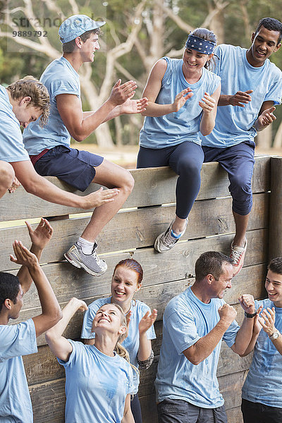 Team klatscht und feiert an der Wand auf dem Bootcamp-Hindernisparcours