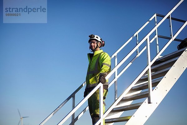 Portrait des Ingenieurs auf der Treppe  im Windpark