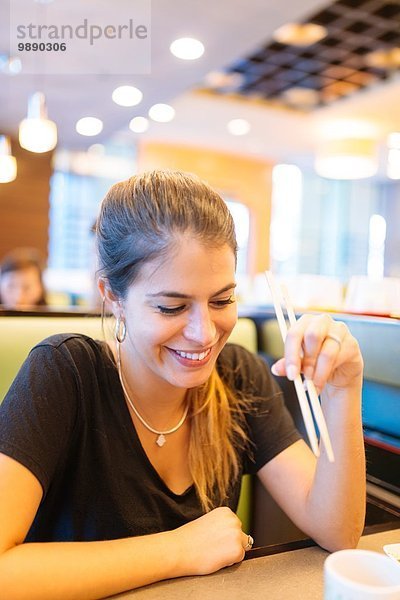 Junge Frau beim Essen mit Stäbchen im Restaurant  Manila  Philippinen
