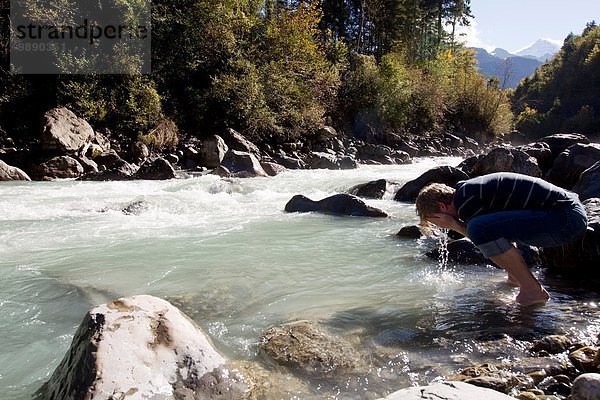 Männlicher Wanderer  der sein Gesicht im Fluss wäscht  Lauterbrunnen  Grindelwald  Schweiz