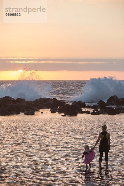 Silhouettiertes weibliches Kleinkind und Mutter beim Paddeln im Meer mit Blick auf Wellen  Kona  Hawaii  USA